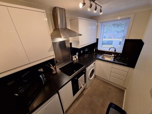 A compact kitchen with a stove, sink, and built-in oven. - Modern Two Bed City Apartment (inverness)