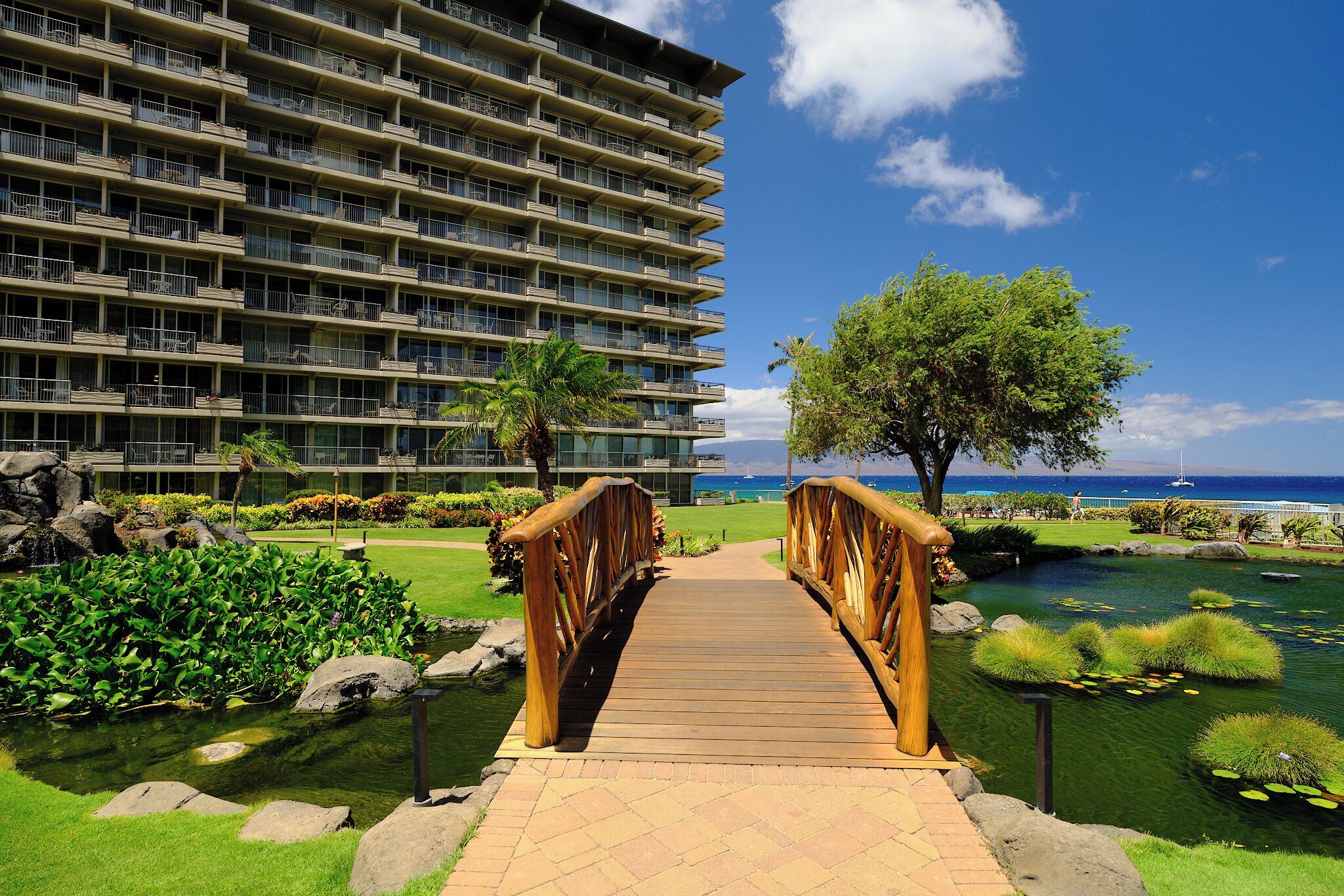 A wooden bridge leading to a hotel with a view of the ocean.