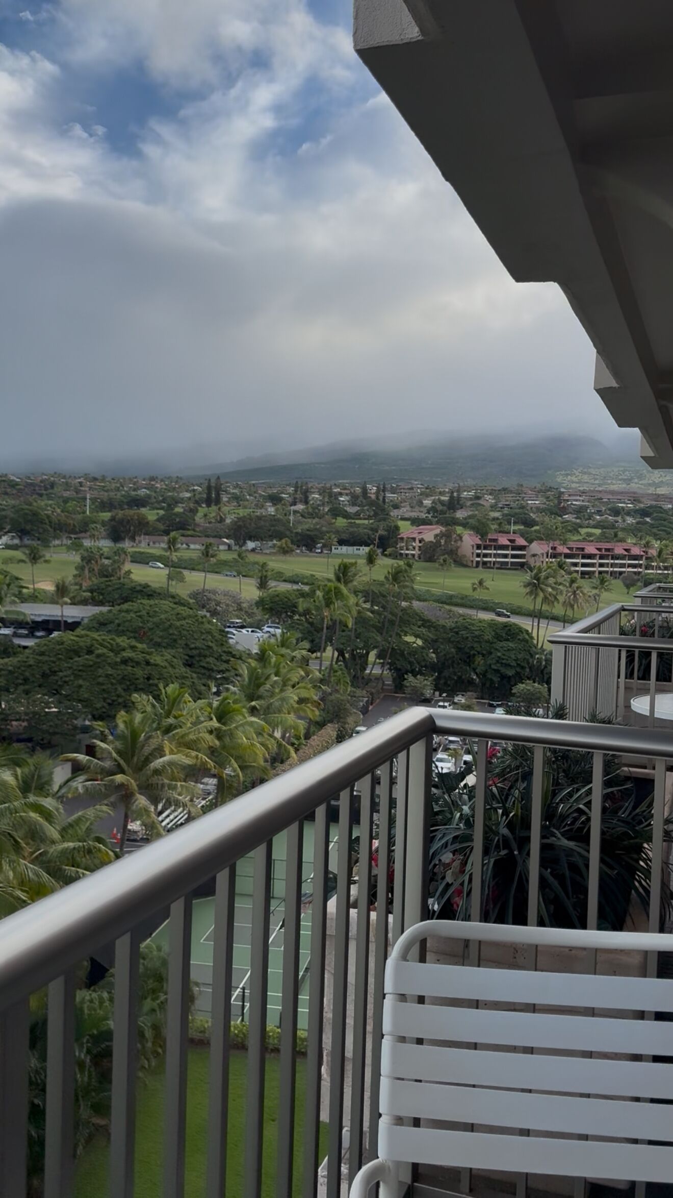 Un balcon donnant sur un quartier résidentiel, avec vue sur les maisons et la verdure.
