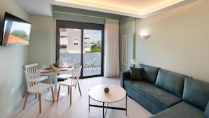 A modern living room with a sofa, a round coffee table, and a dining area with chairs and a table. - Dawn Apartments (Lefkada)
