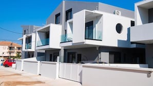 A modern multi-story residential building with balconies, a gated entrance, and a clear sky. - Dawn Apartments (Lefkada)