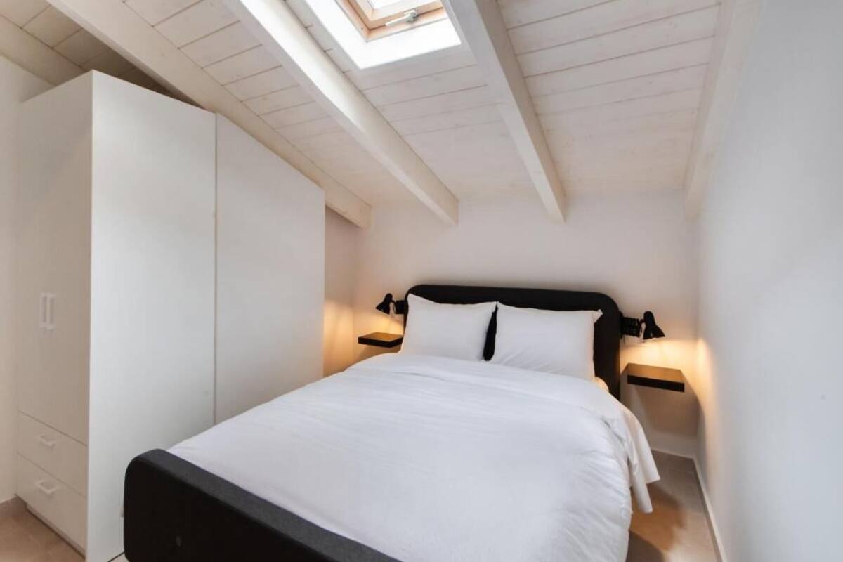 Une chambre à coucher avec un lit, une armoire et une lucarne.