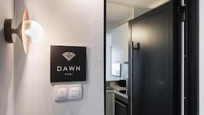 A modern interior with a black door, a wall-mounted light fixture, and a sign reading "DAWN RUBI". - Dawn Apartments (Lefkada)