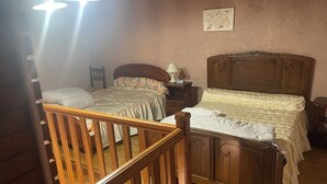 Een slaapkamer met twee bedden, houten hoofdborden, een nachtkastje, een lamp en een aan de muur hangend kunstwerk.