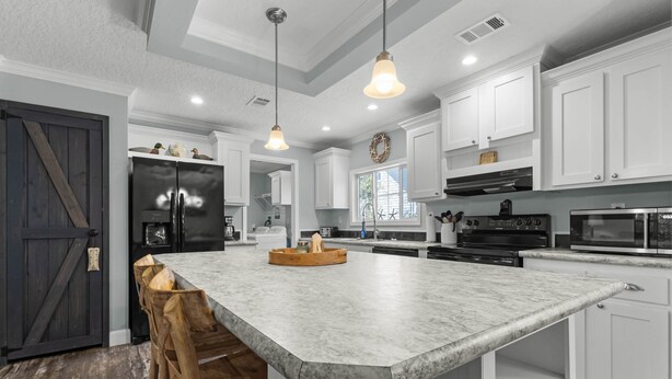 A modern kitchen with white cabinetry, a large island with a marble countertop, and pendant lighting. - Fin & Feather - Steinhatchee Florida (Steinhatchee)