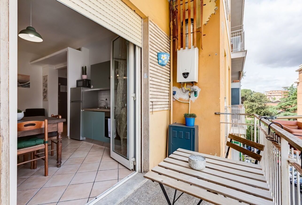 Varanda com mesa, cadeiras, aquecedor de água e vista para a rua.