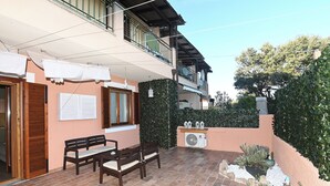 A patio area with a wooden bench, a table, and a fan. - Accogliente appartamento situato a Olbia,
A 2 km dall'aeroporto.. (Olbia)