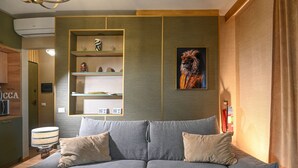 A living room with a grey sofa, beige cushions, a wall-mounted shelf with decorative items, and a framed picture of a lion. - Accogliente appartamento situato a Olbia,
A 2 km dall'aeroporto.. (Olbia)