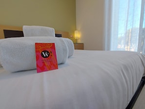 A neatly made bed with white linens and a sign on the bed. - Casa Bon Retorn (L'Escala)