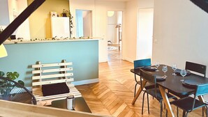 Een eetruimte met een houten visgraatvloer, een blauwe tafel en zwarte stoelen.