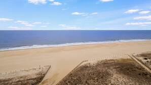 A wide sandy beach with a clear sky and ocean. - Sandpiper Dunes 1009 (Ocean City)