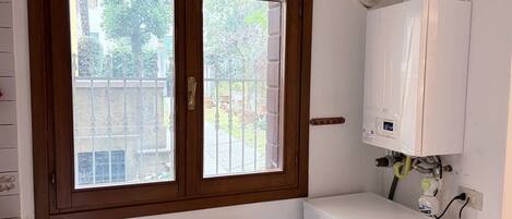 A room with a radiator, a white heater, and a window with a wooden frame.