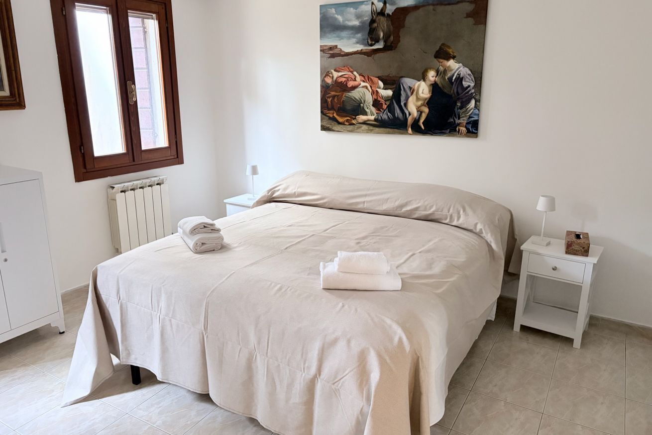 Une chambre à coucher avec un grand lit, un radiateur, une table de chevet et un tableau accroché au mur.