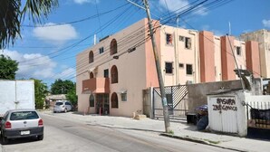 A building with a gated entrance, a parked car, and a streetlight. - Kom Shot 38 (Cancún)