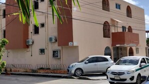 A building with a flat facade, multiple windows, and a parking area with cars. - Kom Shot 38 (Cancún)