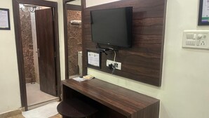 A small, private bathroom with a wooden vanity, a mirror, and a mounted television. - Staylo Masterprice Palace (Lucknow)