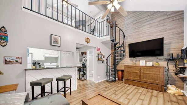 A spacious living area with a sofa, a wooden coffee table, a TV, and a kitchen in the background. - Cozy Beach Retreat Near Whitecap & Padre Island (Corpus Christi)