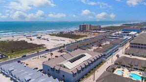 A coastal hotel with multiple buildings, a parking lot, and a beach view. - Cozy Beach Retreat Near Whitecap & Padre Island (Corpus Christi)