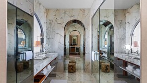 Un baño lujoso con pisos de mármol, lavamanos dobles y espejos amplios.