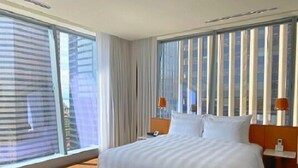 A hotel room with a large bed, two bedside tables, and a view of the city through floor-to-ceiling windows. - Elegant Seattle High-Rise King Suite w/ Spa & Skyline Views (Seattle)