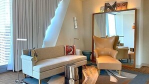 A modern hotel room with a sofa, armchair, and a large mirror. - Elegant Seattle High-Rise King Suite w/ Spa & Skyline Views (Seattle)