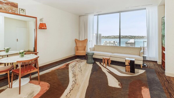 Ein modernes Hotelzimmer mit Essbereich, einer Couch und einem großen Fenster mit Blick auf die Stadt.