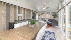 Een moderne eetruimte met een houten tafel, witte stoelen en een grijze bank.