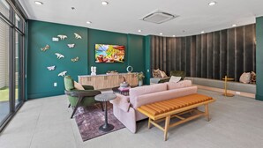 Una sala de estar moderna con paredes color turquesa, un banco de madera, un sillón verde y un sofá rosa.