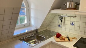 Eine Küche mit Spüle aus Edelstahl, einer Holzarbeitsplatte, einem Schneidebrett mit Gemüse und einem Herd.