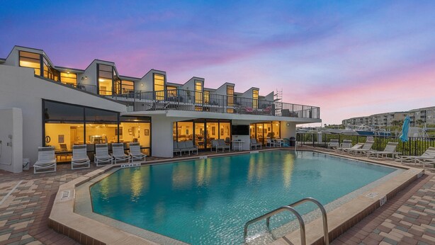 A modern hotel with a swimming pool, outdoor seating, and a sunset view. - Marker 33 #2d3 (New Smyrna Beach)