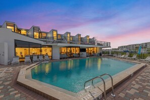 A modern hotel with a swimming pool, outdoor seating, and a sunset view. - Marker 33 #2d3 (New Smyrna Beach)