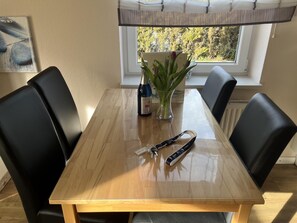 A dining table with chairs, a vase with flowers, a bottle, and a keychain. - Small Fiete vacation apartment (Wittdün)
