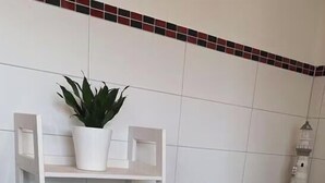 A white shelving unit with folded towels, a potted plant, and a small decorative item. - Large Fiete vacation apartment (Wittdün)