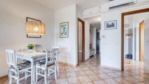 Un comedor con una mesa y sillas blancas, una lámpara colgante y una computadora portátil.