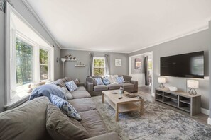 A living room with a sectional sofa, a coffee table, a TV, and a fireplace. - Nice home near Mashpee Commons and all Falmouth has to offer (Falmouth)