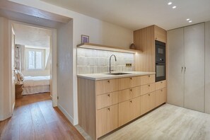 Een moderne keuken met houten kastjes, een inbouwoven en een groot raam.