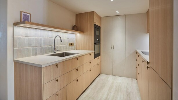 A modern kitchen with light wood cabinetry, a white countertop, a stainless steel sink, and a built-in oven. - Luxurious Apartment Place Vendome - Rue de la Paix (Paris)
