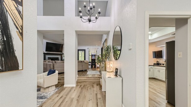 A spacious living area with a high ceiling, a fireplace, and a modern chandelier. - The Casa Cantera by Six Flags, La Cantera, The Rim. 3Br Home with Pool & Cabana (San Antonio)