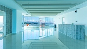 A spacious lobby with a glass wall offering a view, a reception desk, and a clear ceiling. - 12H Luxury Ocean Views of Panama Canal (Panama City)