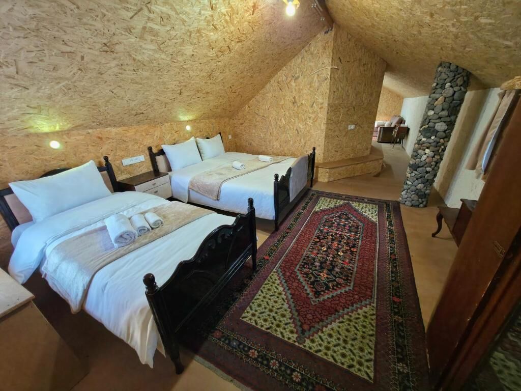 Un dormitorio con dos camas, un pilar de piedra y techo de madera.