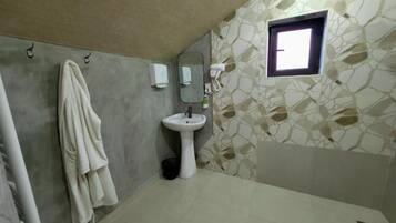 A bathroom with a stone-patterned wall, a sink, a towel rack, and a window.