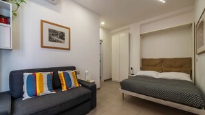 Un dormitori modern amb un llit, un sofà, un quadre amb marc i un armari.