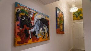 A hallway with two large abstract paintings on the walls and a chandelier hanging from the ceiling. - The Red Door (Bangor)