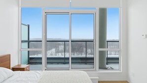 Quarto com uma grande porta de correr de vidro que dá para uma varanda com vista para uma paisagem coberta de neve.