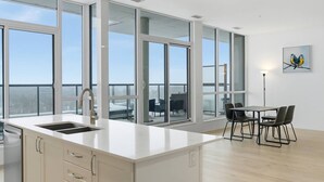 Uma cozinha moderna com uma ilha grande, uma área de jantar com cadeiras e janelas amplas com vista.