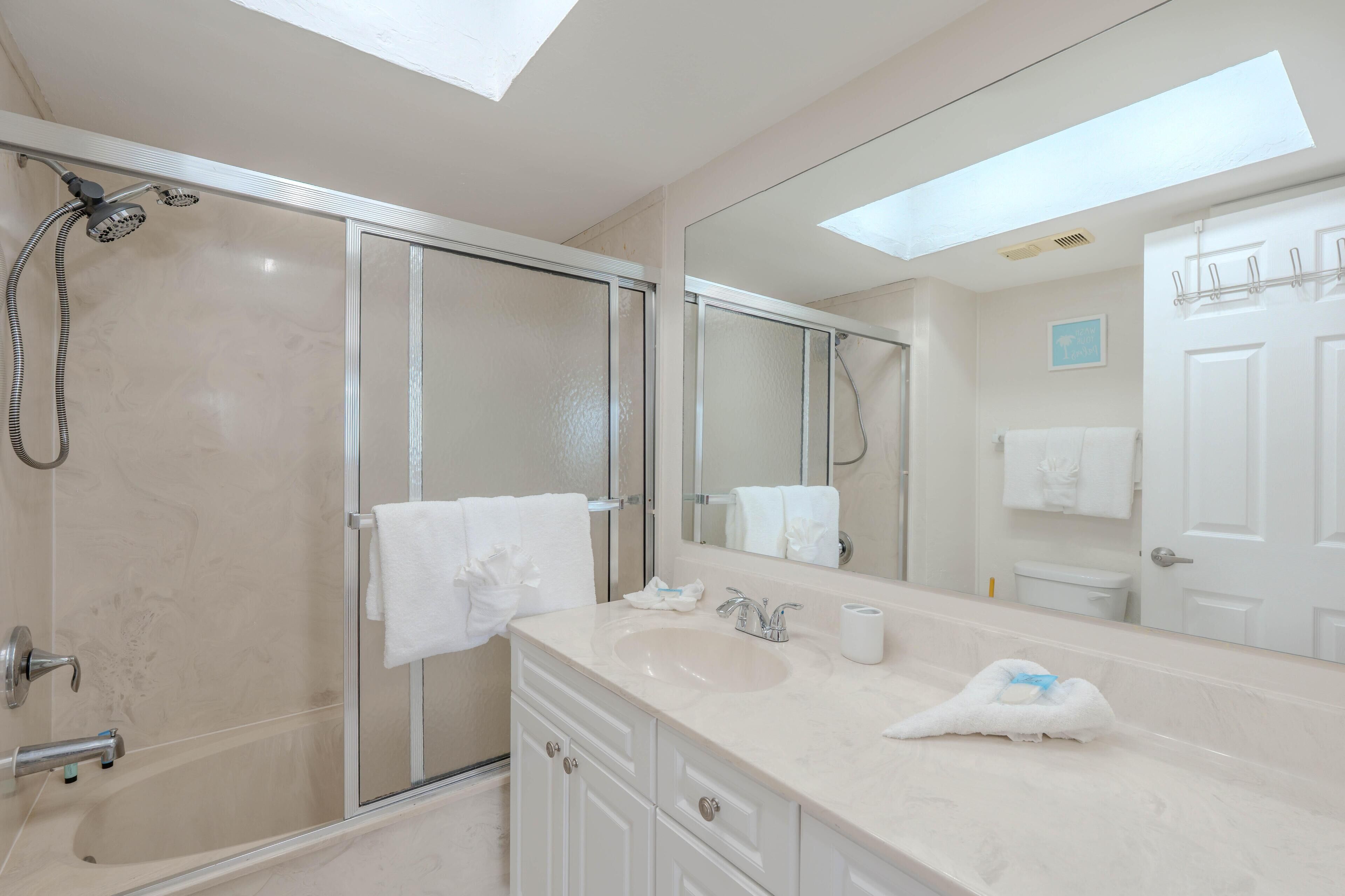 Une salle de bain moderne avec une douche à parois de verre, un grand miroir, un lavabo et des toilettes.