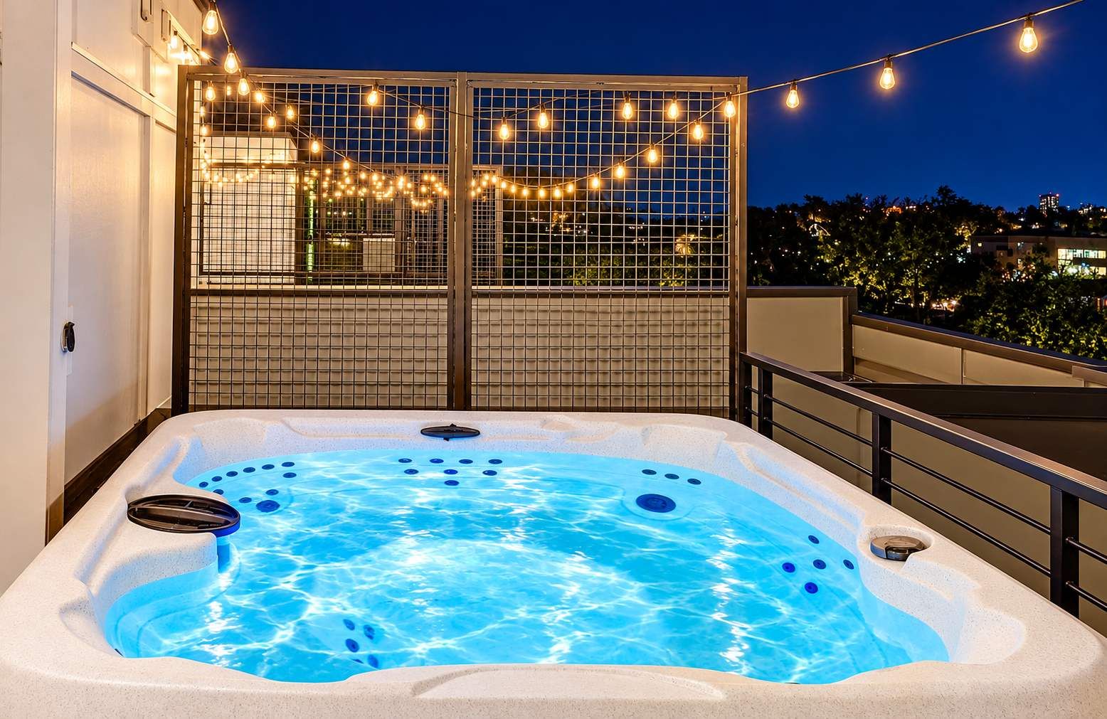 Un jacuzzi con piscina, rodeado por un balcón con guirnaldas luminosas.