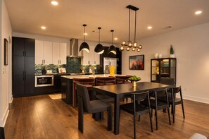 A modern kitchen with dark cabinetry, a central island, and pendant lighting. - Stylish 3BR Nash Escape | Hot Tub + Skyline Views! (Nashville)
