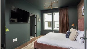 Quarto com cama, televisão, janela e porta.