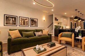 A modern living room with a green sofa, a yellow armchair, and a coffee table with books and a decorative item. - Stunning Lux Nash Home | Rooftop Firepit | 10 Beds (Nashville)